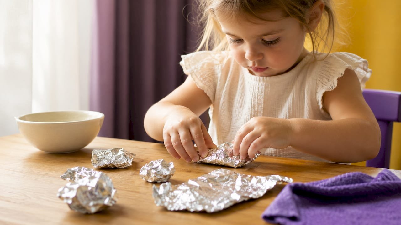 Toddler shaping kitchen foil by hand