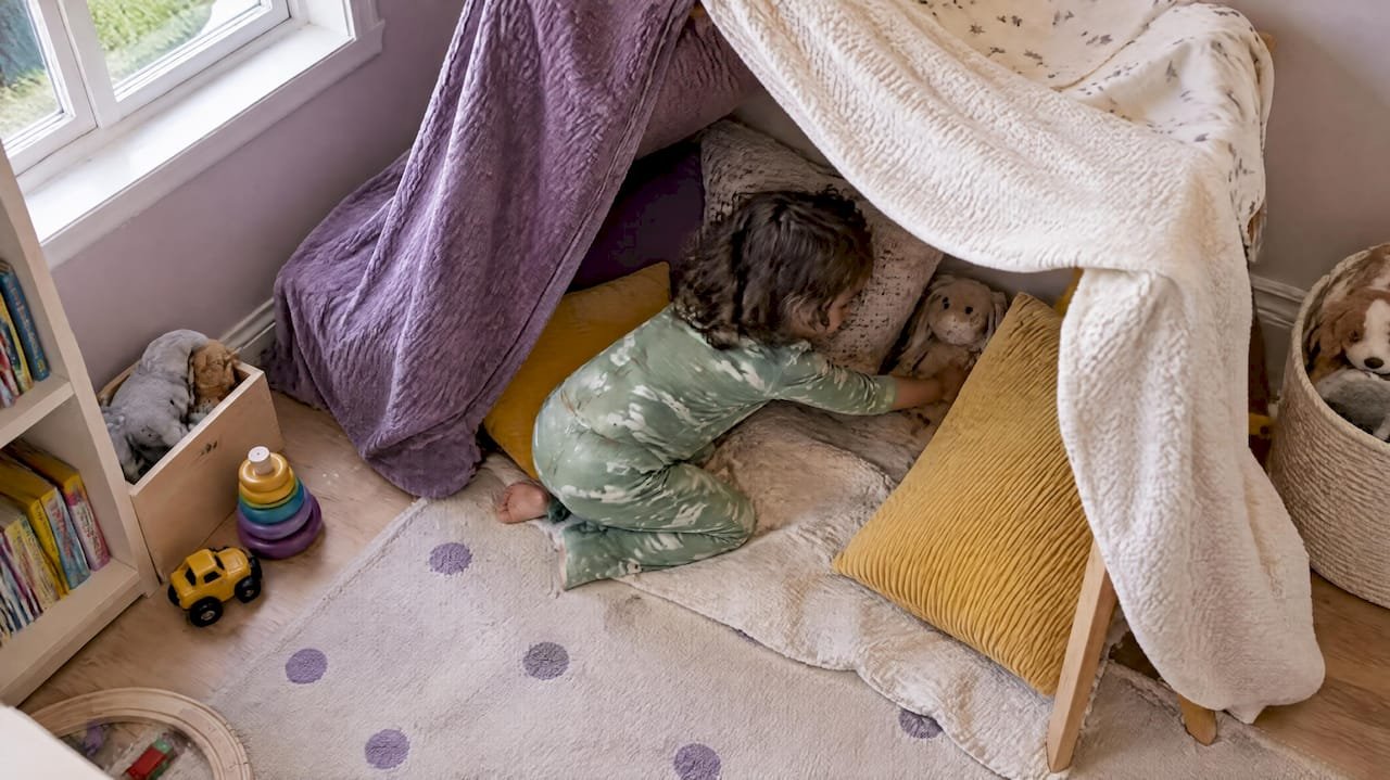 Toddler searching for stuffed animals inside fort