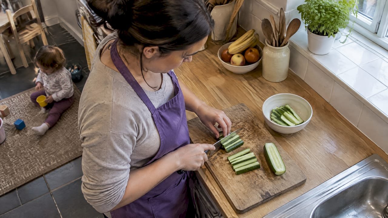 Caregiver cutting cucumber into batons