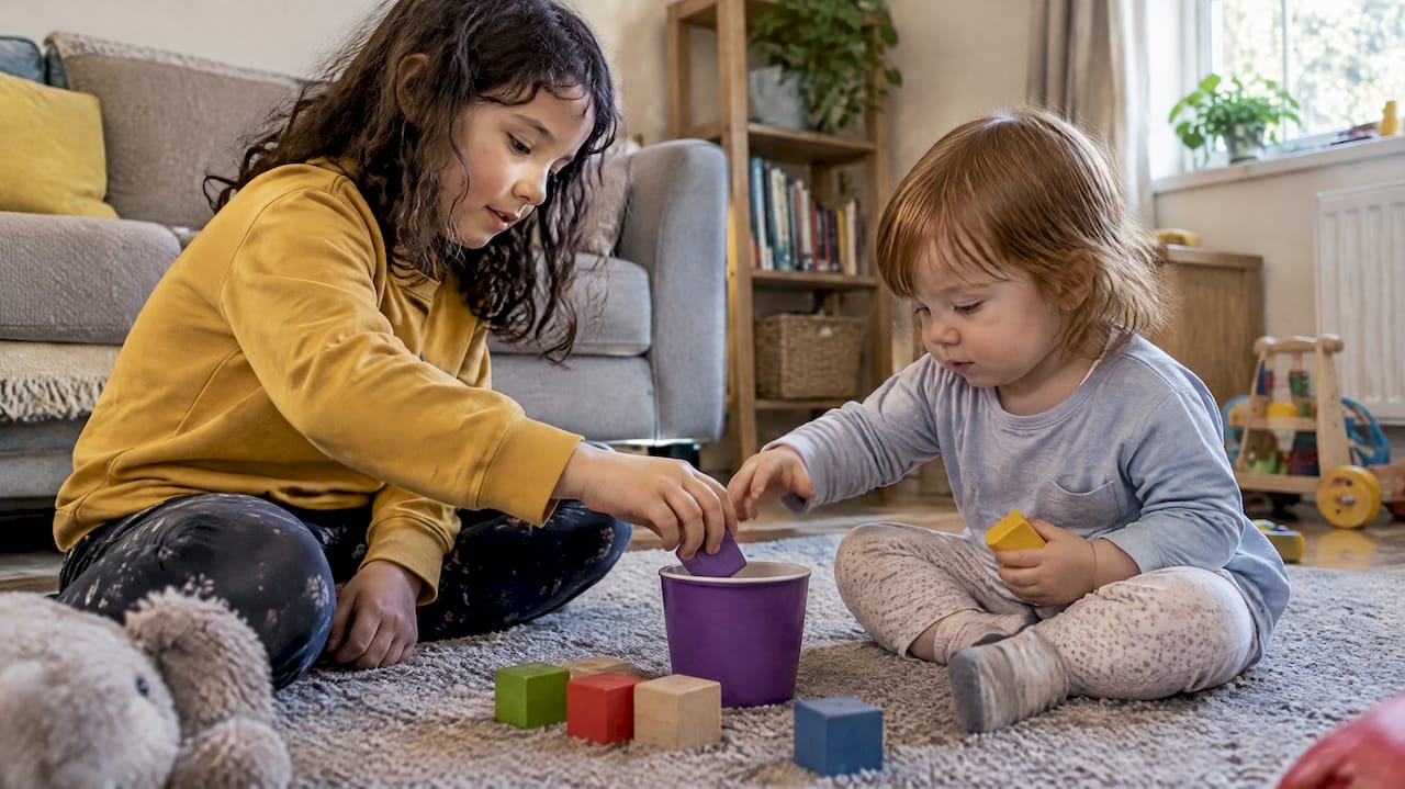 Siblings count blocks into a cup together