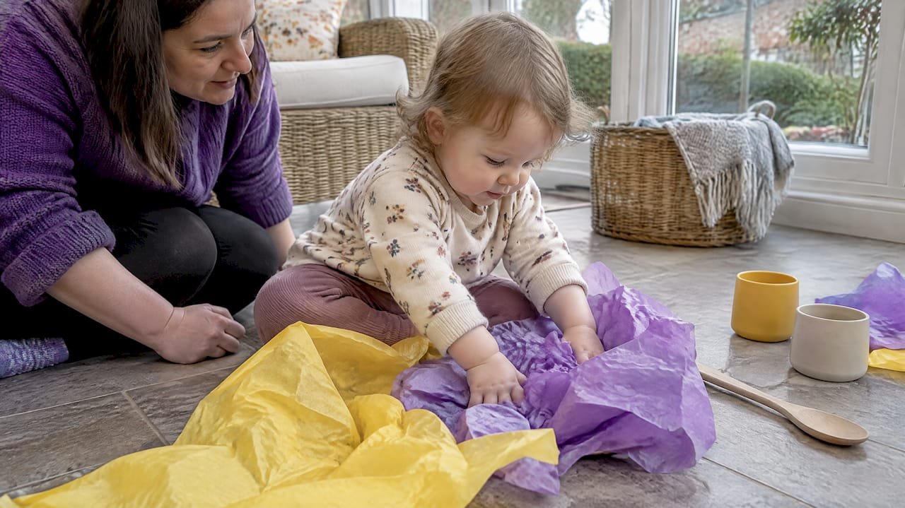 Toddler feeling tissue paper during sensory play